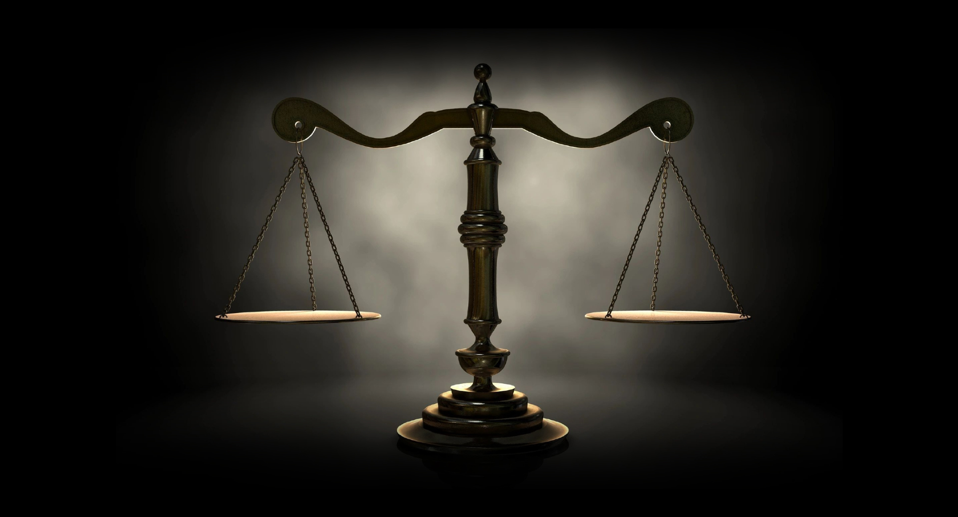 Balanced justice scales on a table with a dark background