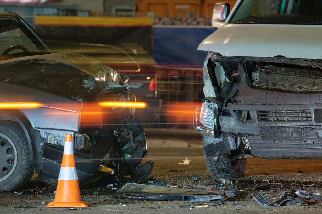 Damaged in heavy car accident vehicles after collision on city street crash site at night. Road safety and insurance concept.